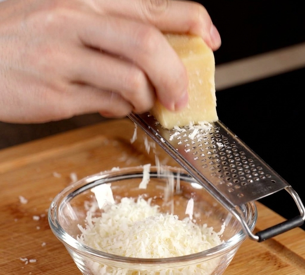 Grattugiare un blocco di parmigiano in una ciotolina con un tuorlo duovo crudo.