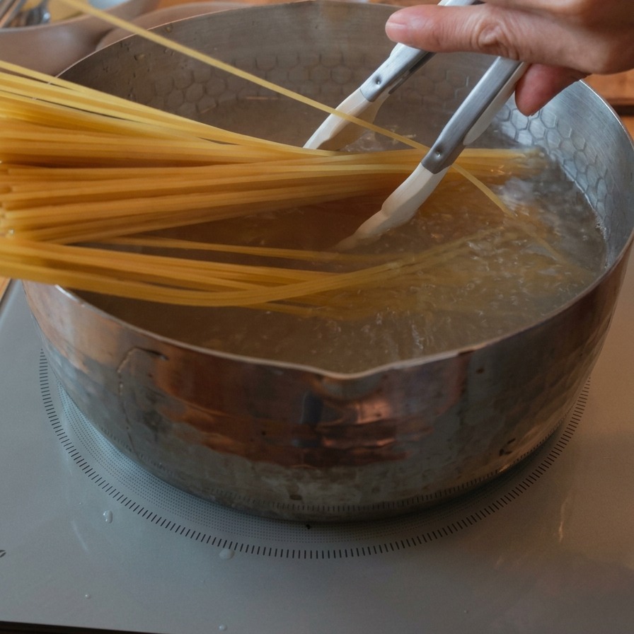 Spaghetti secchi che vengono immersi in una pentola di acqua bollente con laiuto di una pinza.