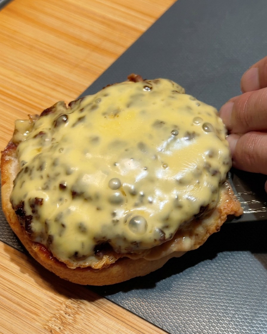 Una spatola che trasferisce due hamburger sovrapposti e ricoperti di formaggio fuso sulla base del panino.