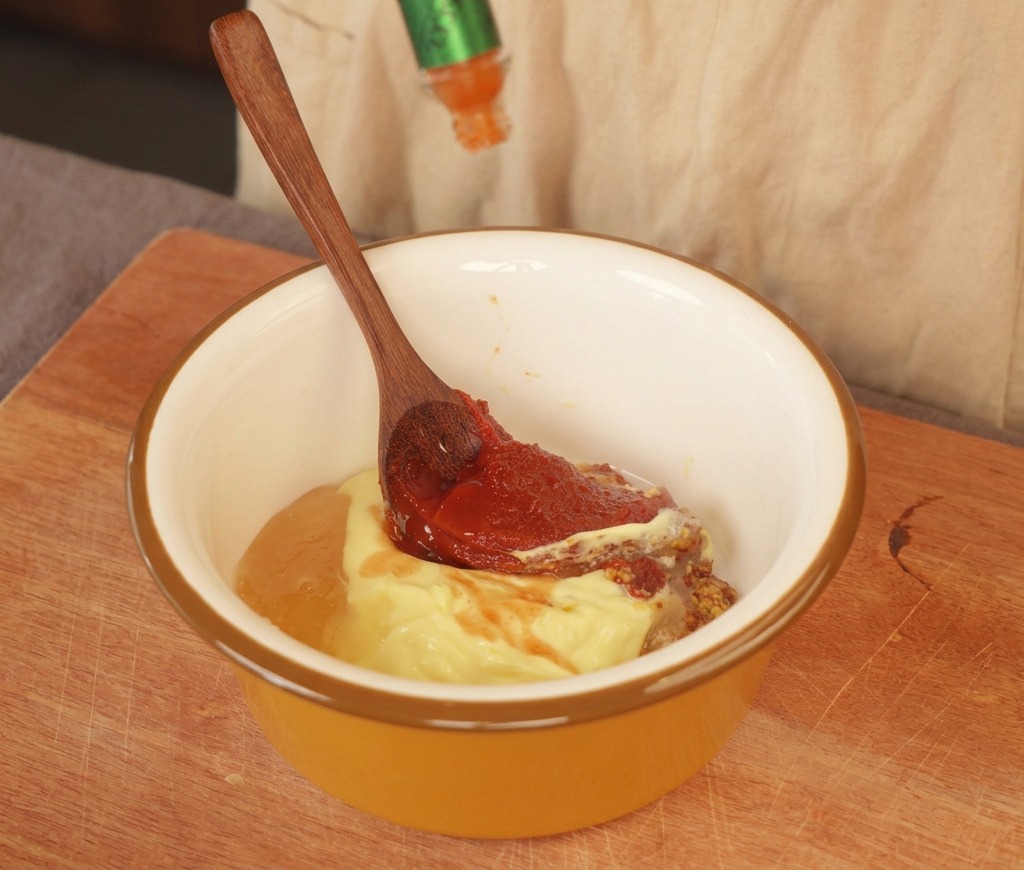 Salsa piccante versata in una ciotola gialla con maionese, senape e pasta rossa.