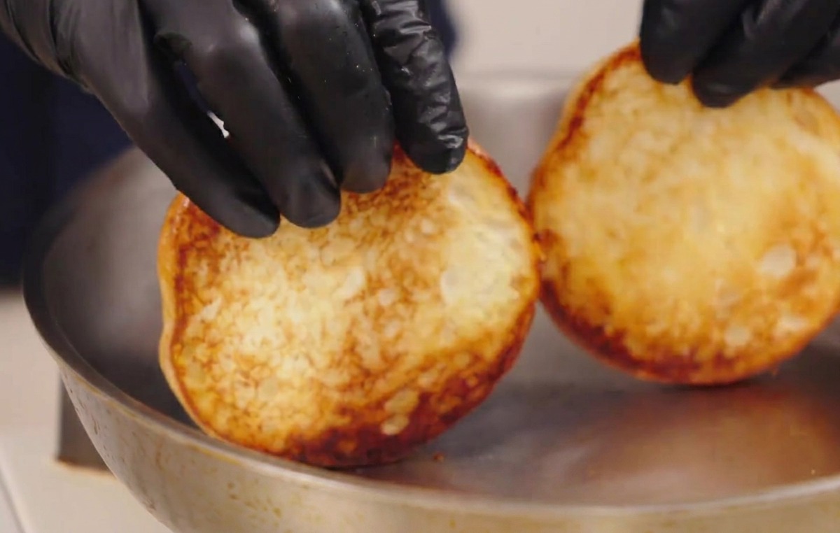 Mani che sollevano i panini tostati mostrando la superficie dorata e caramellata.