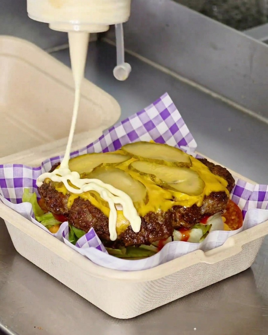 Maionese bianca spruzzata a zigzag sopra un cheeseburger.