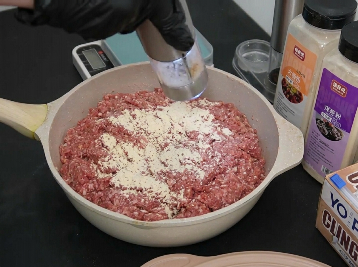 Una mano con guanto macina una piccola quantità di sale marino sulla carne condita.