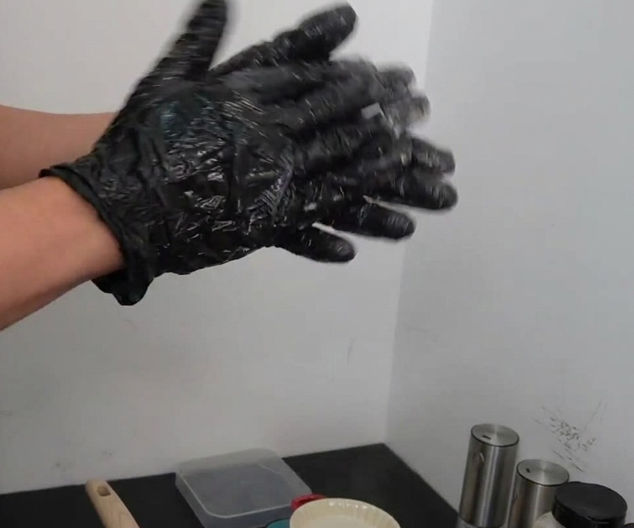 Mani con guanti che lanciano e colpiscono una palla di carne condita tra i palmi.