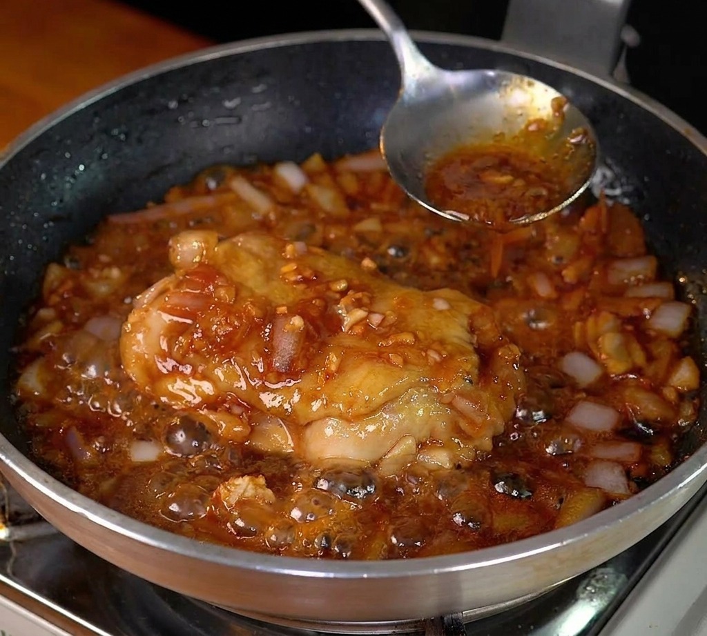 Pollo che sfrigola in una salsa scura e densa con cipolle appassite.