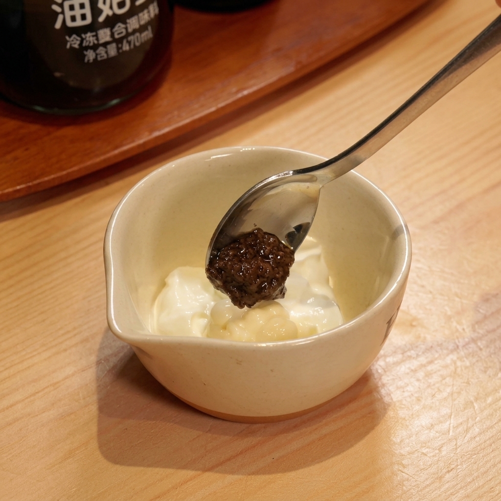Cucchiaio con crema di tartufo nero sopra la salsa bianca allo yogurt.