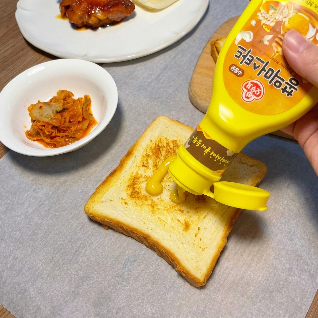 Senape gialla applicata a zigzag su una fetta di pane tostato dorato.