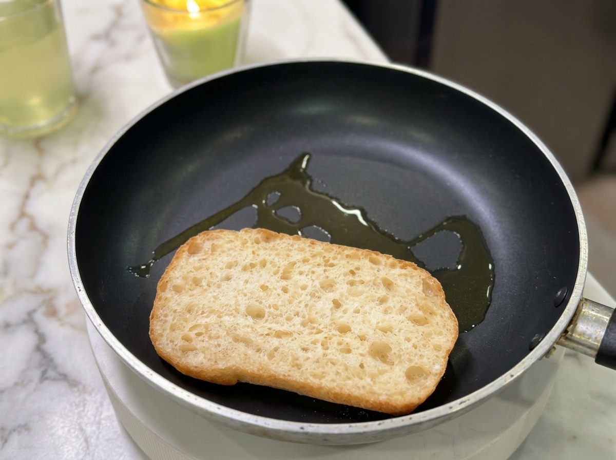 Metà di una ciabatta che tosta in una padella piatta con un filo dolio.