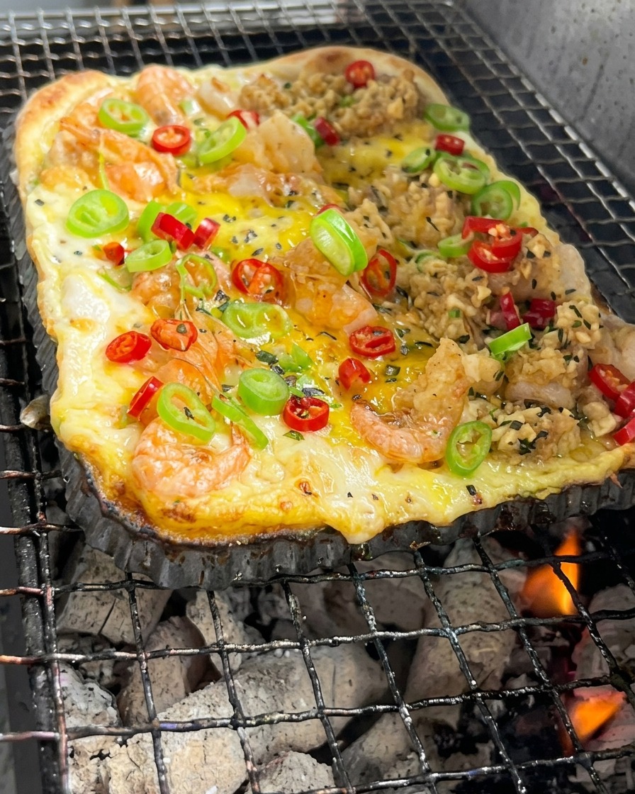 La base della pizza rettangolare con gamberi e verdure cuoce sopra le braci ardenti del carbone.