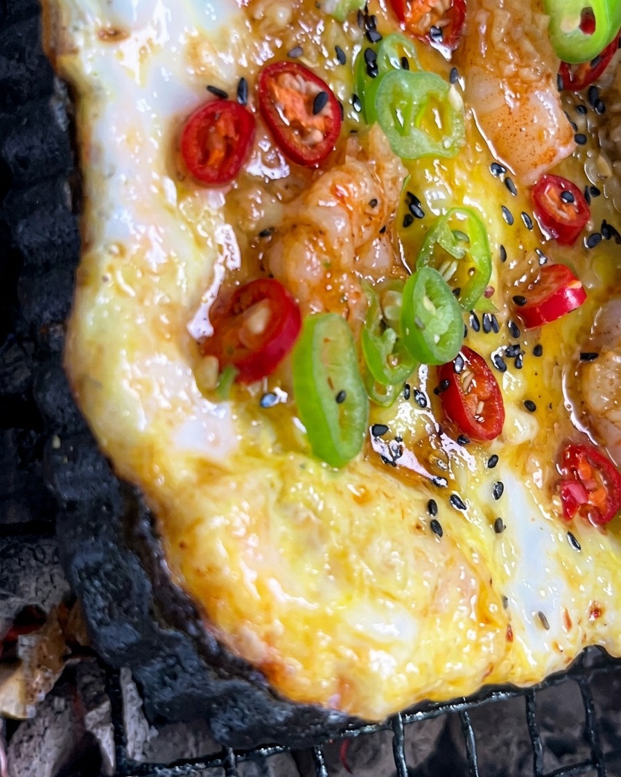 Salsa allaglio tritato spennellata su una pizza colorata in cottura sul barbecue.