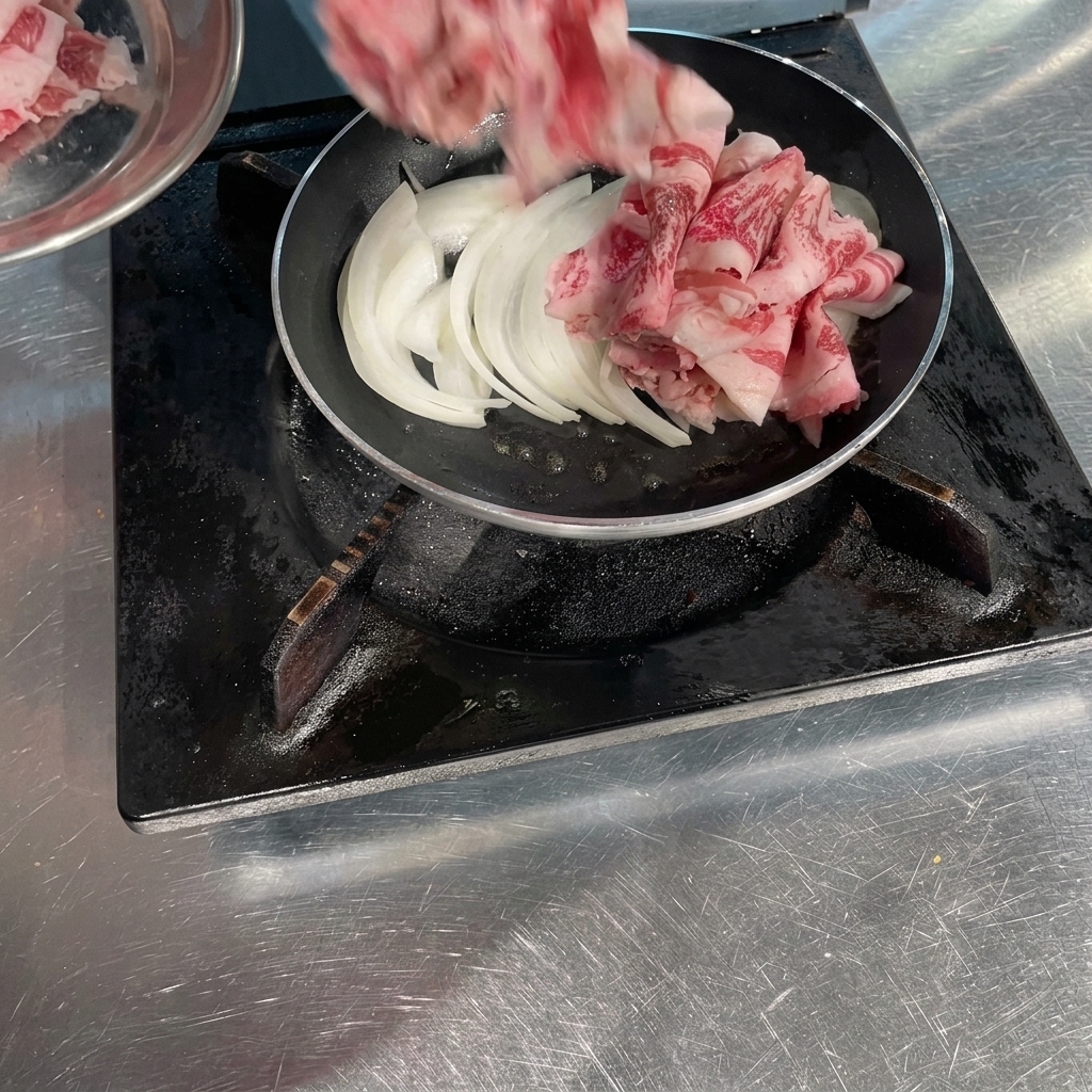 Fette sottilissime di manzo crudo arrotolate che vengono disposte in padella sopra le cipolle bianche soffritte.