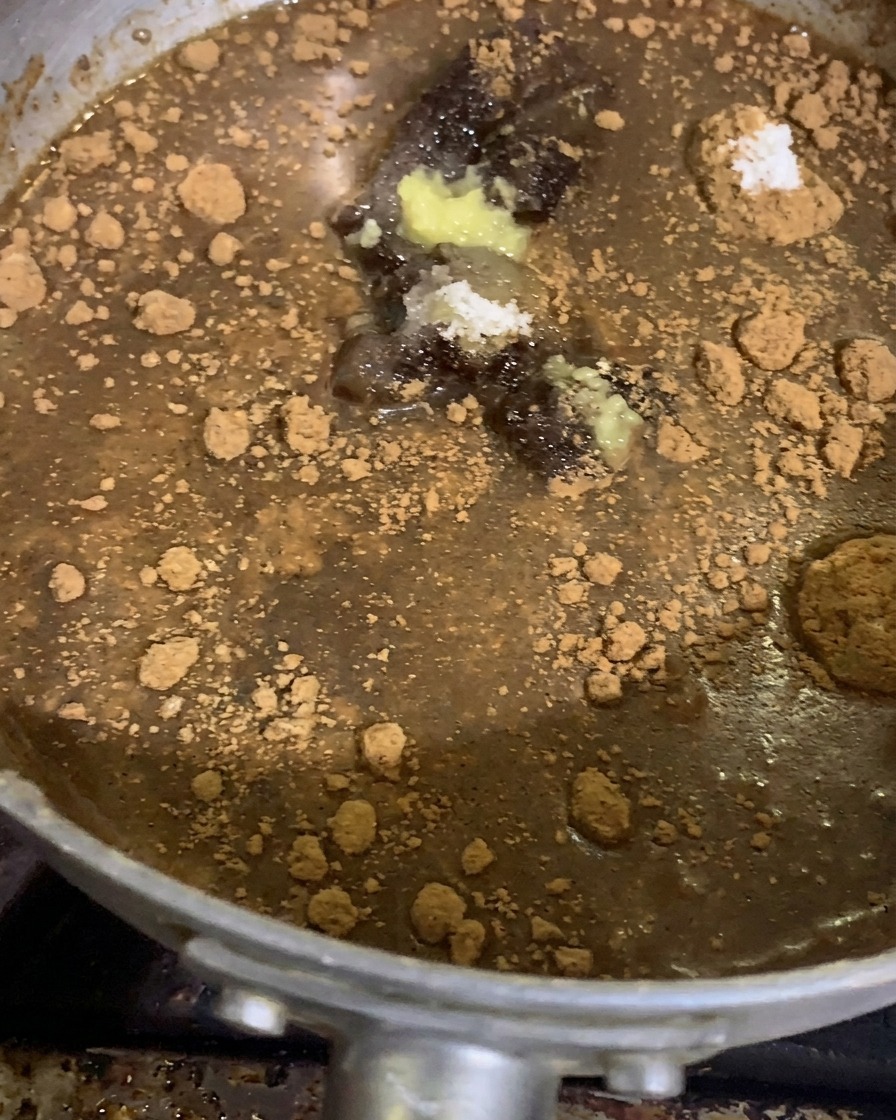 Spezie macinate, aromi in polvere, pasta daglio e zenzero adagiati su una base densa di salsa al miso in un pentolino dargento prima della cottura.