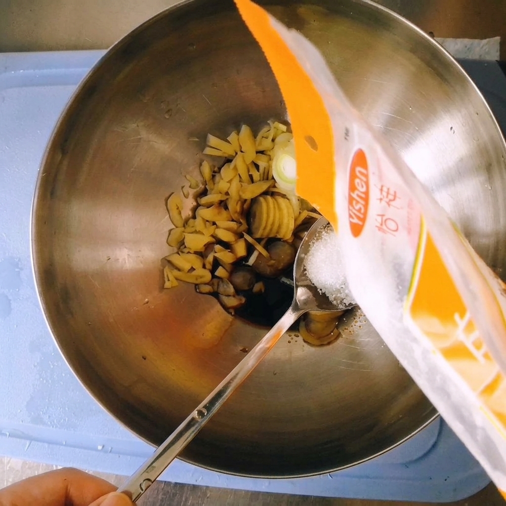Versare lo zucchero semolato bianco da una confezione di plastica su un cucchiaio tenuto sopra la ciotola.