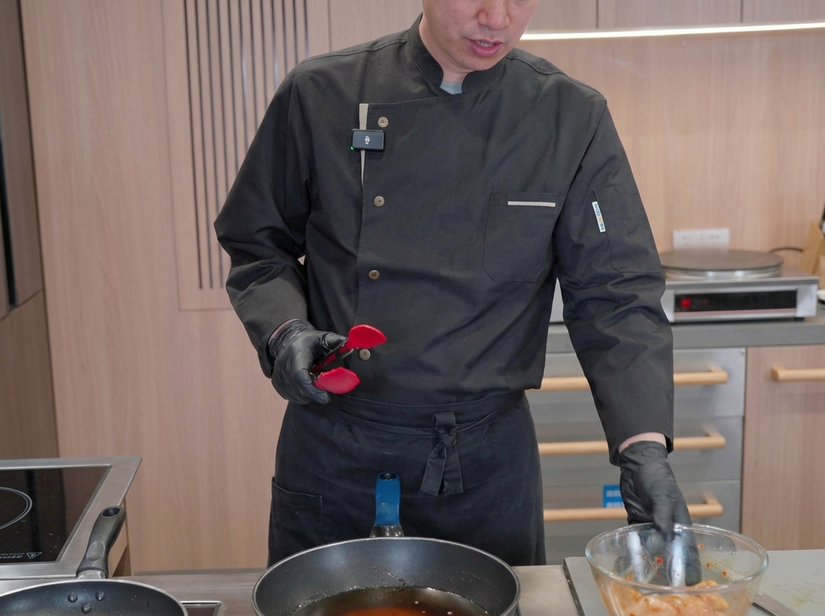 Pezzi di calamaro marinato che cuociono in una grande padella piena di olio bollente e spumeggiante mentre lo chef controlla la frittura.