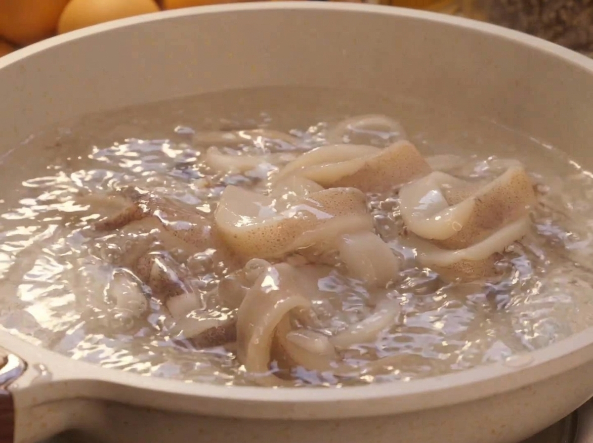 Anelli di calamaro freschi che sbollentano in una pentola dacqua in piena ebollizione.