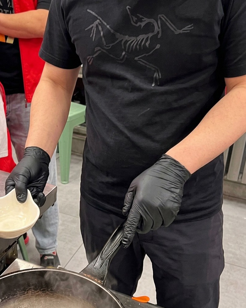 Pezzi di calamaro incisi che vengono sbollentati brevemente in una pentola di acqua bollente con vapore che sale.