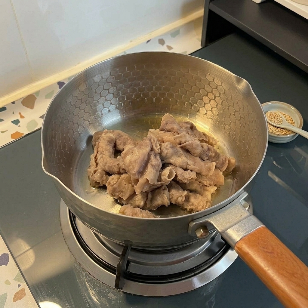 Sottili fette di manzo fatte saltare in una pentola in acciaio inossidabile su un fornello a gas.