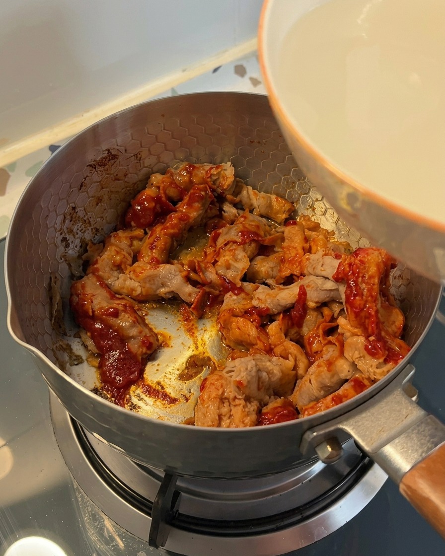 Acqua opaca di lavaggio del riso versata da una ciotola bianca in una pentola con la carne di manzo.