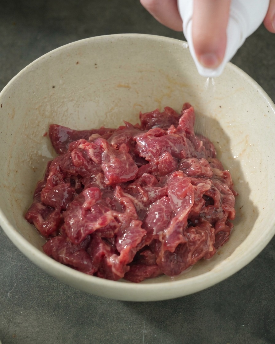 Spruzzata di olio su una ciotola di manzo marinato.