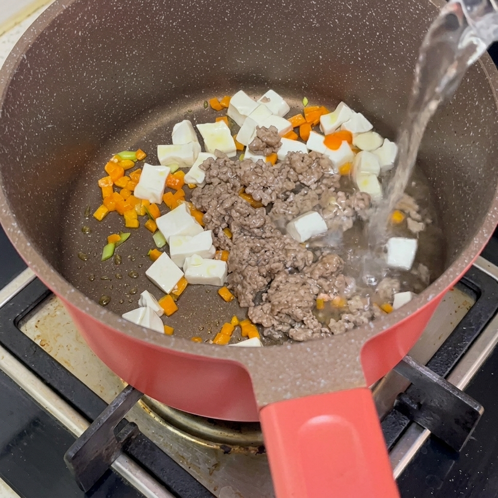 Cubetti di tofu sbollentati, manzo saltato e carote tritati uniti in pentola mentre viene versata acqua bollente.