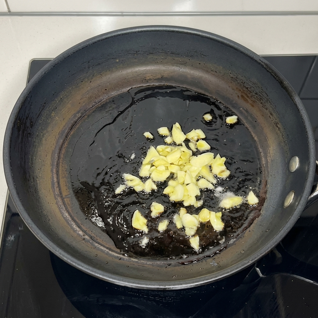 Aglio tritato che soffrigge nellolio caldo.