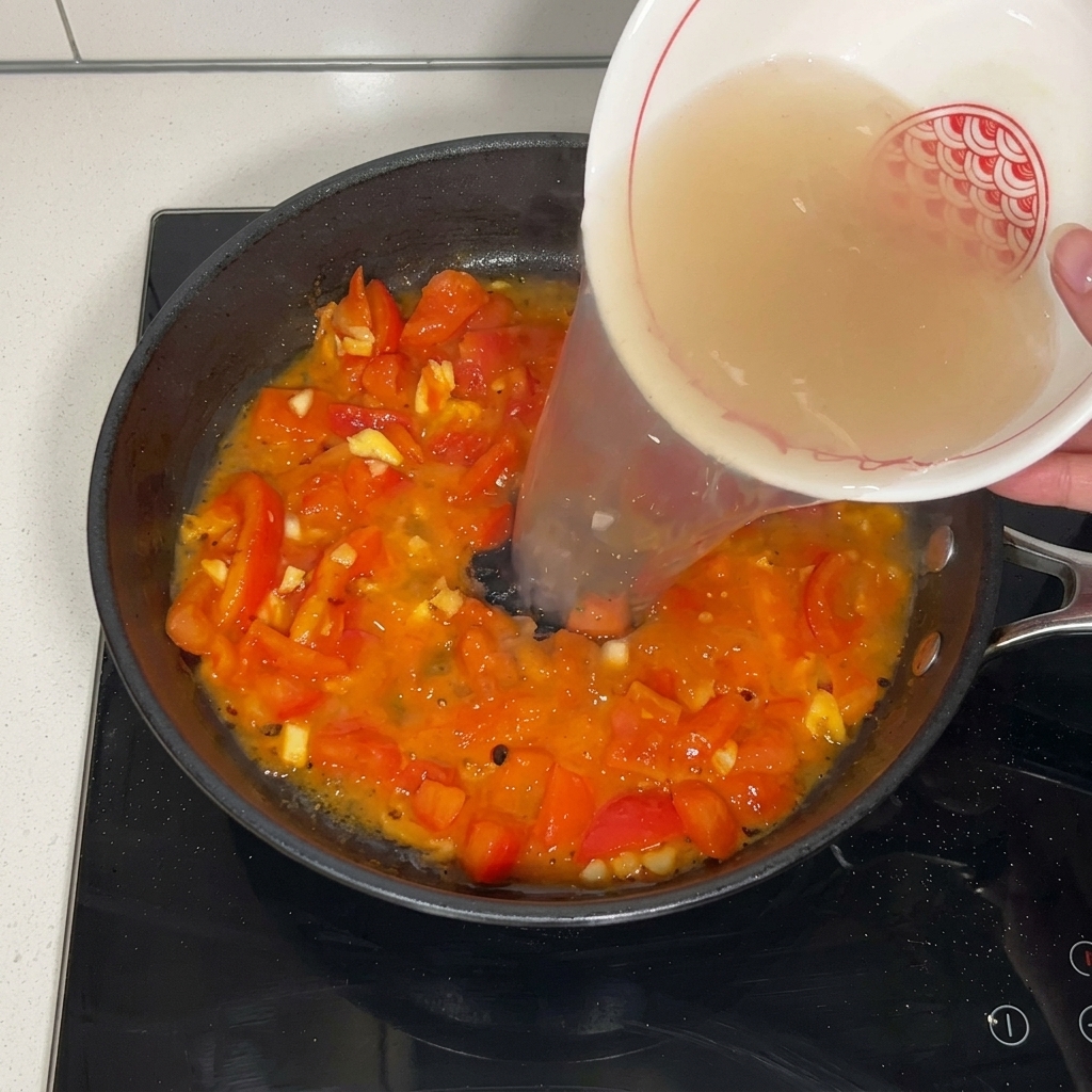Brodo di manzo versato sui pomodori in padella.