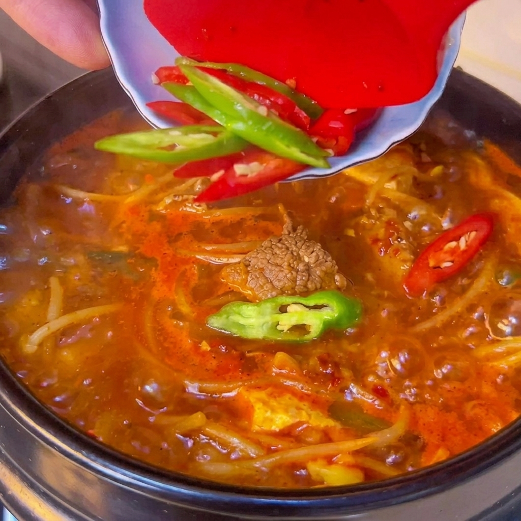 Peperoncini affettati sparsi sulla superficie della zuppa bollente.