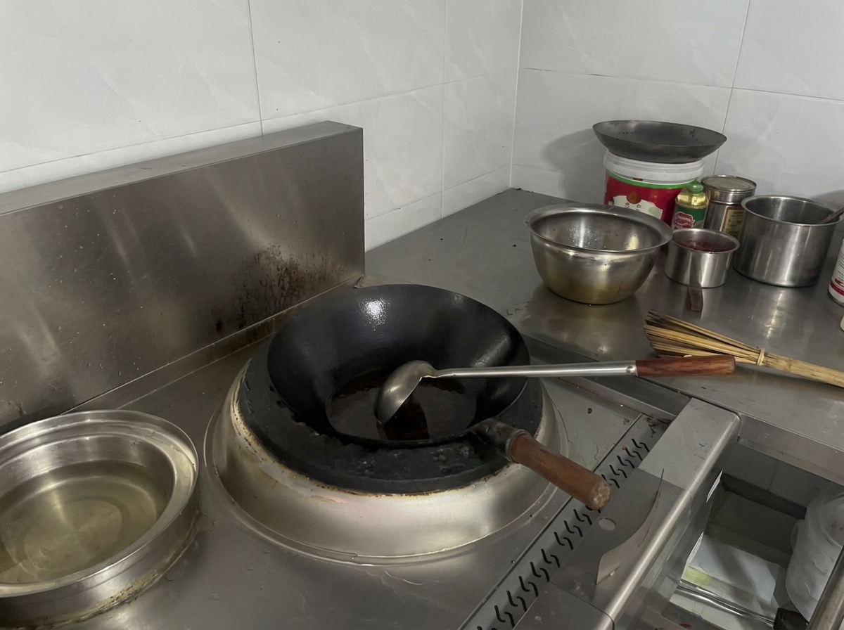 Un wok nero su un fornello pieno di un liquido sobbollente rosso-marrone scuro.