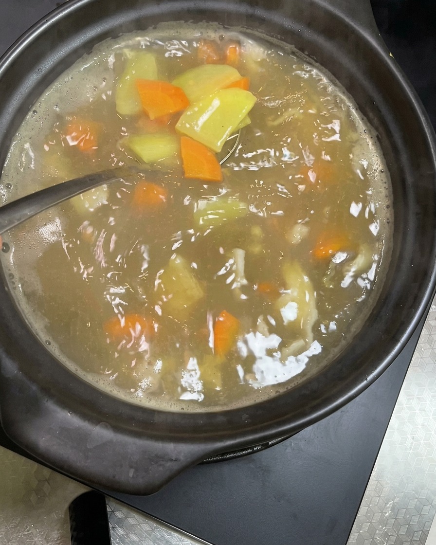 Germogli di soia freschi e croccanti versati nello stufato bollente di verdure e maiale.