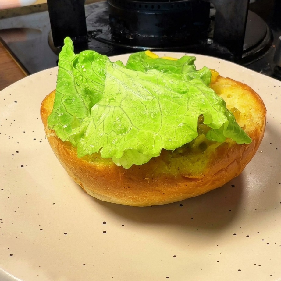 La base di un panino tostato sormontata da una fresca e verde foglia di lattuga.
