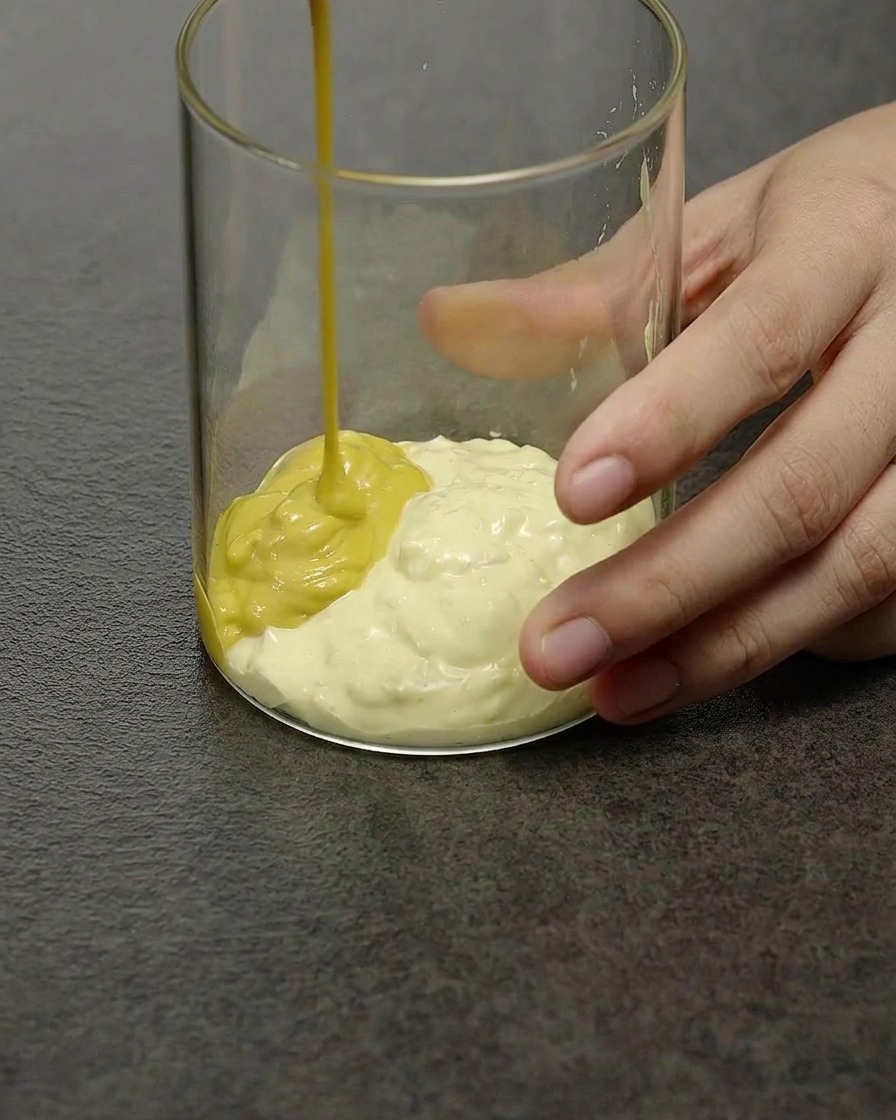 Una cremosa salsa per hamburger giallo pallido mescolata allinterno di una ciotolina di vetro trasparente.
