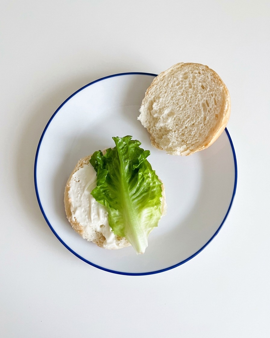 Lattuga verde fresca adagiata sulla metà inferiore del pane condito.