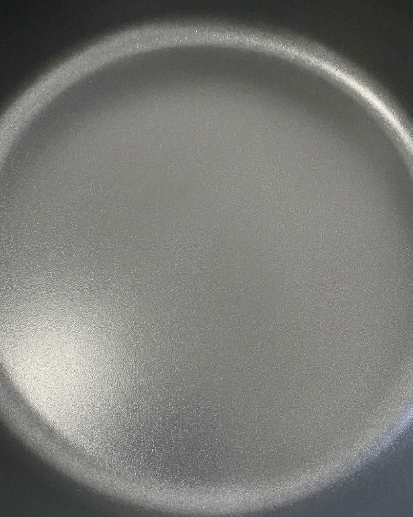 Due fette di cheddar che si sciolgono magnificamente sopra gli hamburger di manzo in una padella scura.