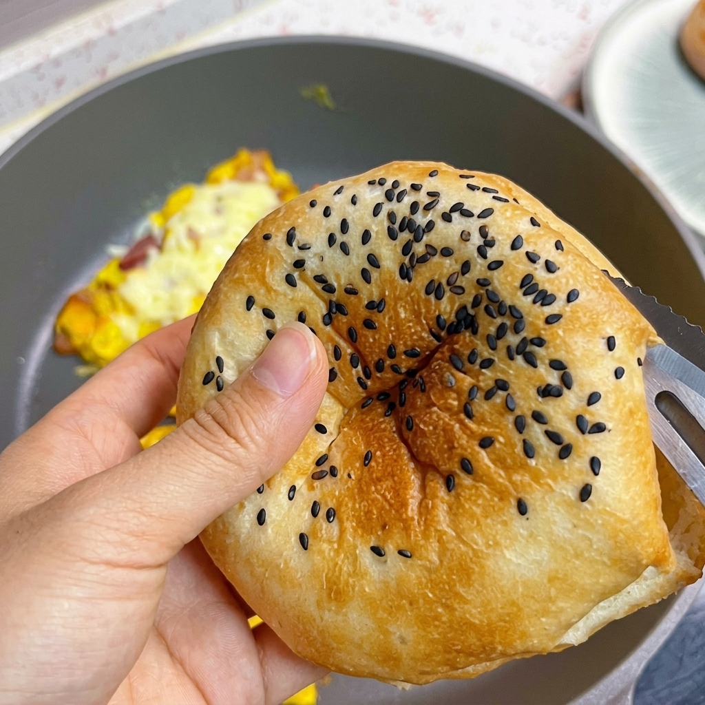 Un panino da hamburger tostato con semi di sesamo nero mentre viene tagliato a metà.