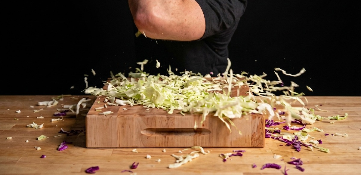 Cavolo cappuccio verde e rosso fresco tagliato finemente su un grande tagliere di legno.