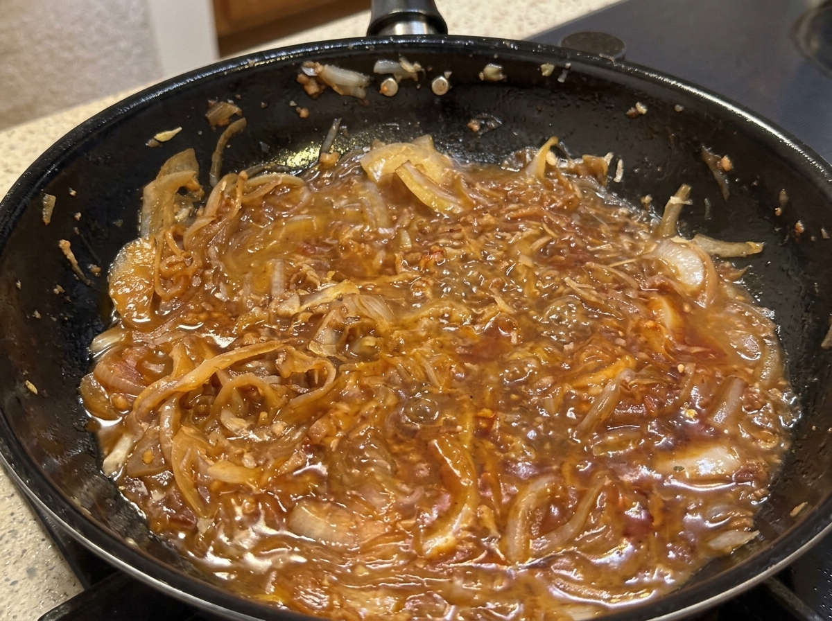 Parmigiano grattugiato in padella con la salsa di cipolle mentre viene versata la panna.