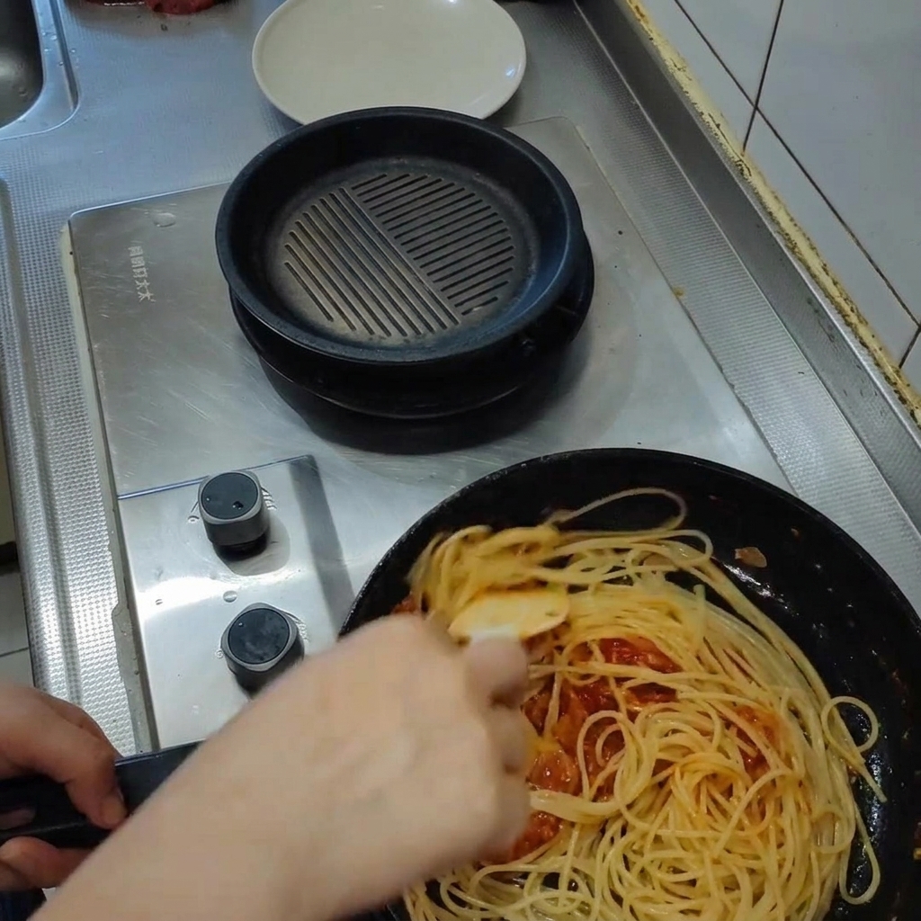 Pasta che viene saltata in padella con il sugo, diventando lucida e cremosa.