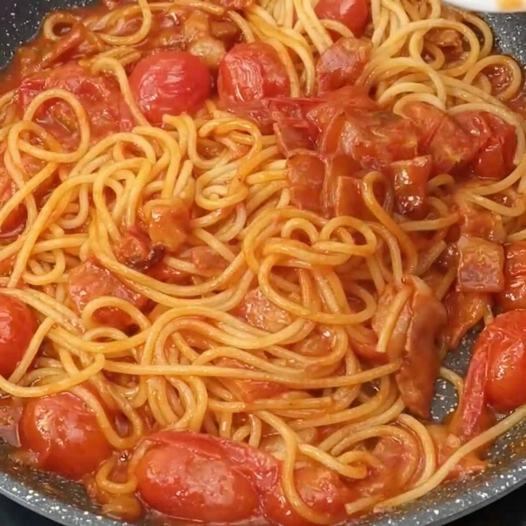 Spaghetti conditi in padella cosparsi di formaggio grattugiato.