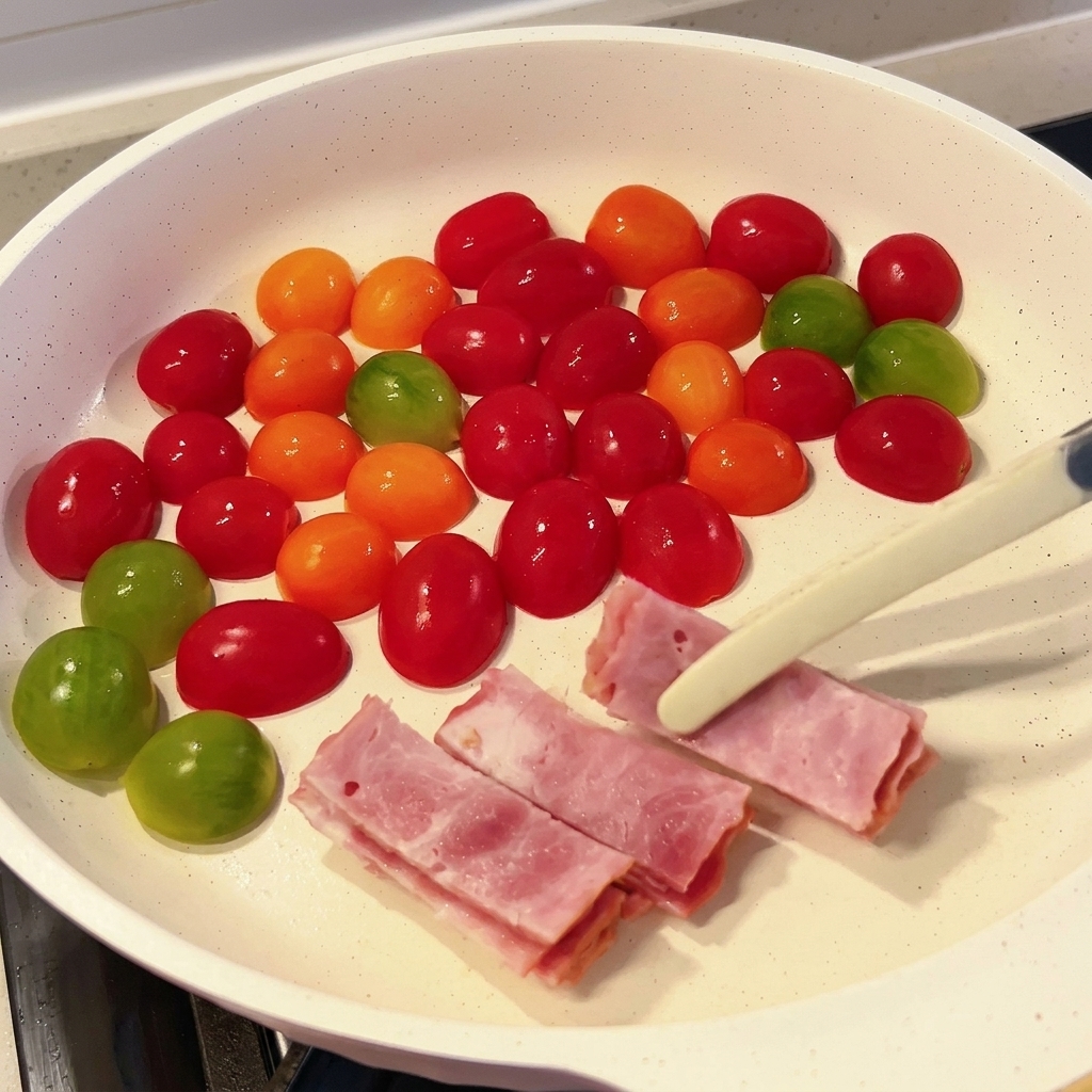 Strisce di pancetta aggiunte nella padella con i pomodorini.
