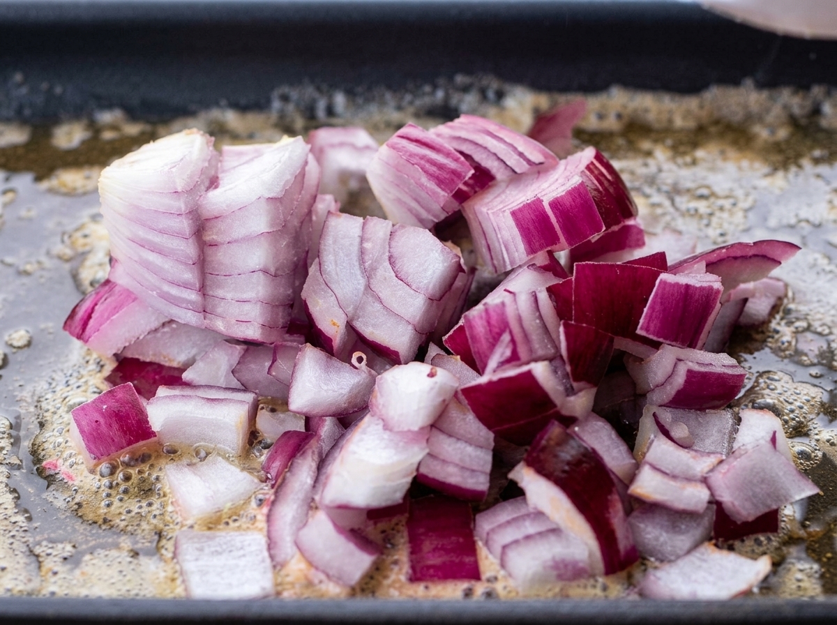 Cipolla tritata che sfrigola nel burro fuso in padella.