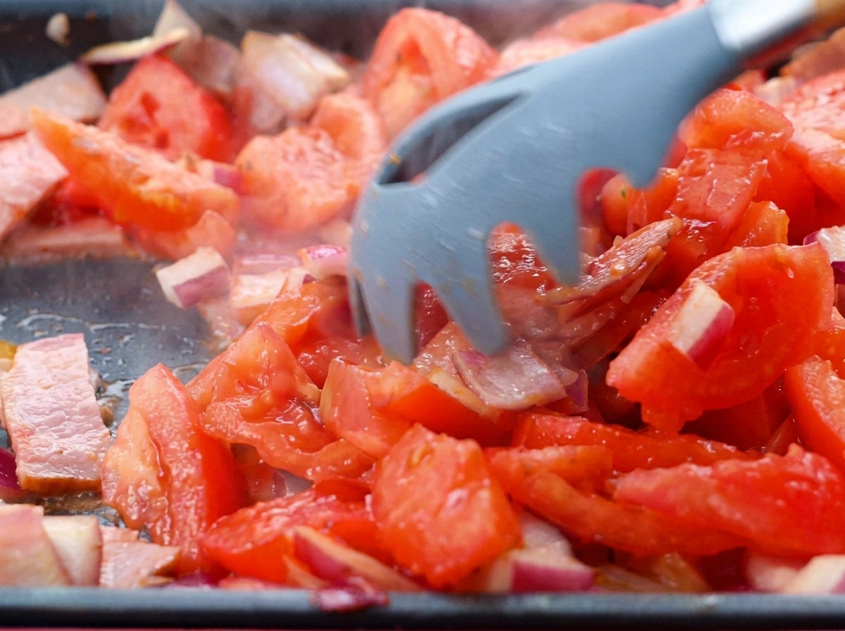 Pomodori a cubetti aggiunti al soffritto di pancetta e cipolla.