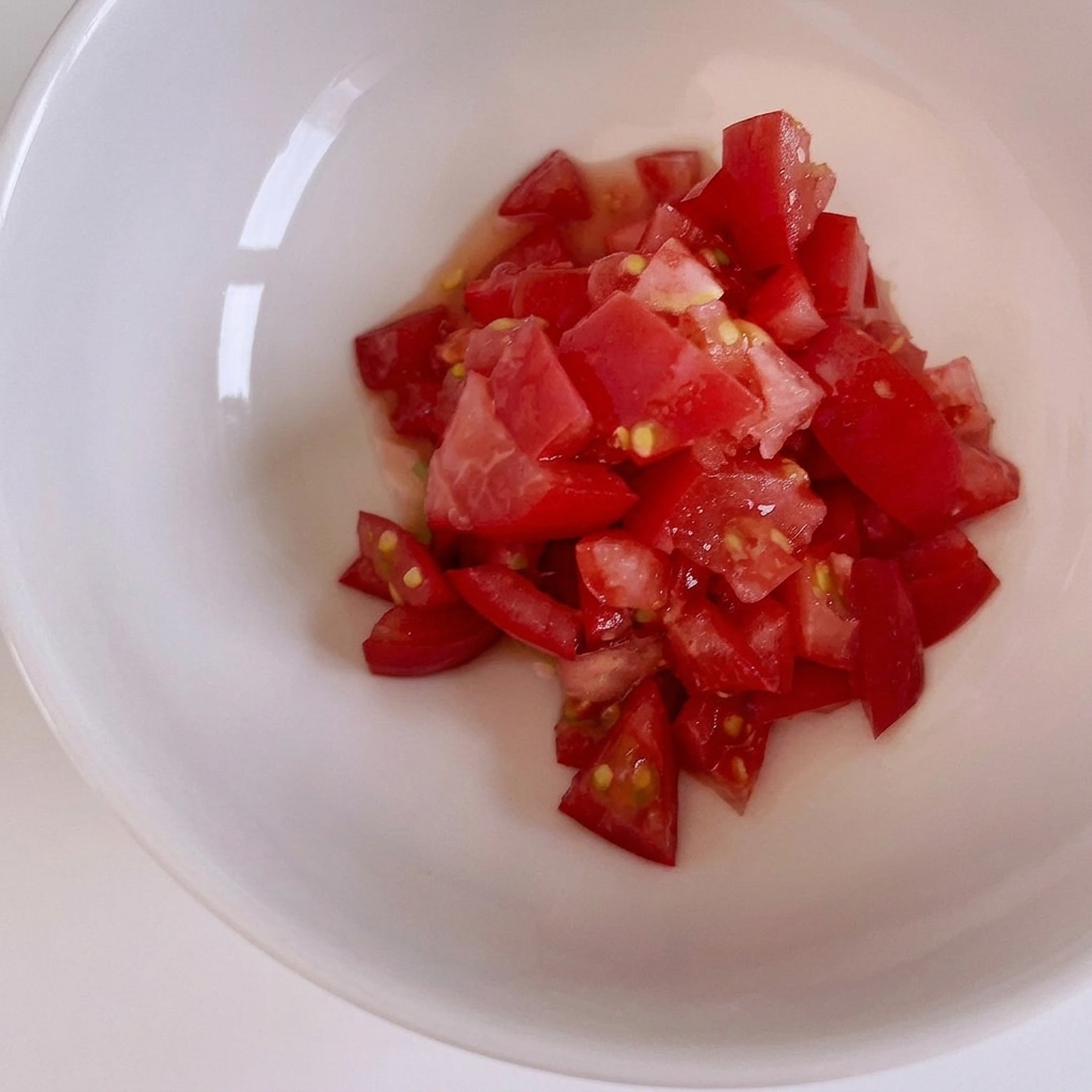 Pomodori rossi freschi tagliati a piccoli cubetti su un tagliere di legno.