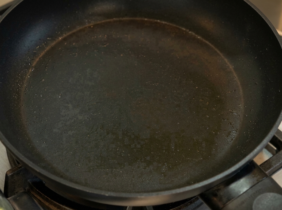 Una frittatina sottile gialla che viene ripiegata in una padella antiaderente.