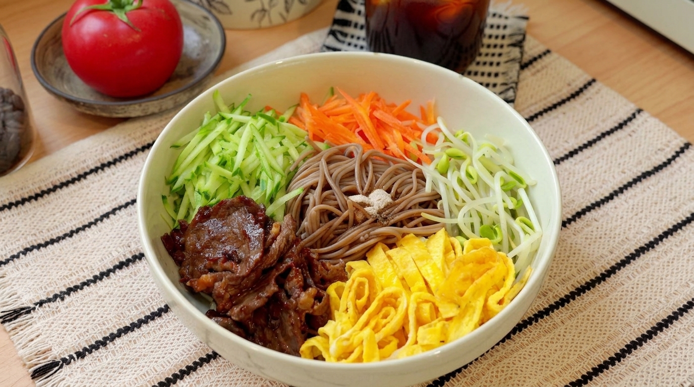 Una ciotola di noodles soba freddi guarniti con manzo saltato, verdure fresche alla julienne e straccetti di uovo.