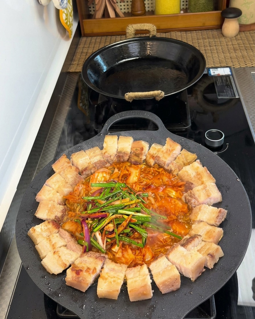 Pancetta e kimchi in padella guarniti con porri freschi, cipolle e condimenti vari.