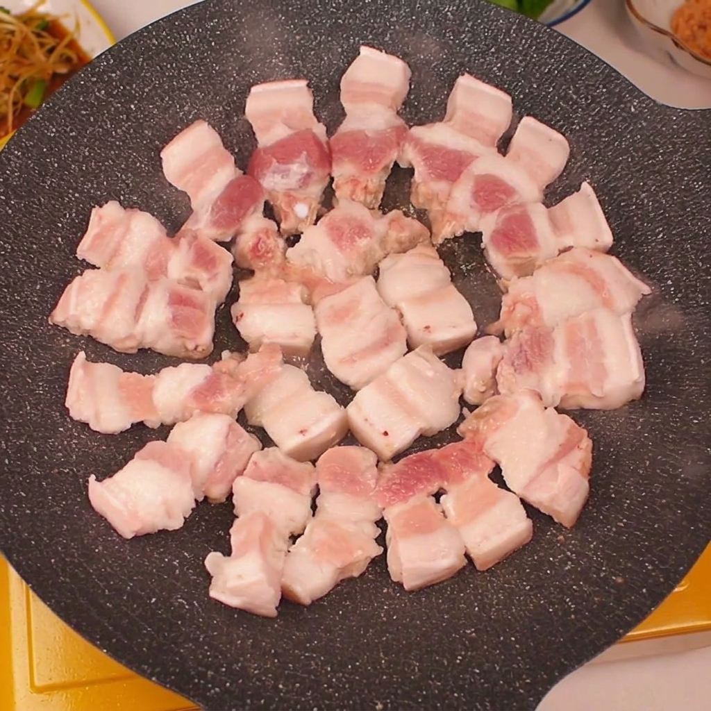 Fette di pancetta fresca disposte in cerchio su una piastra calda.
