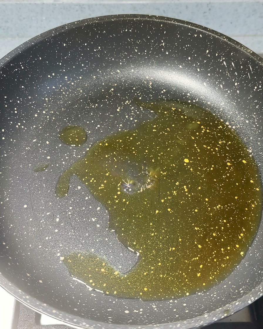 Aglio tritato e pasta di gamberetti rossa che sfrigolano nellolio caldo di una padella.