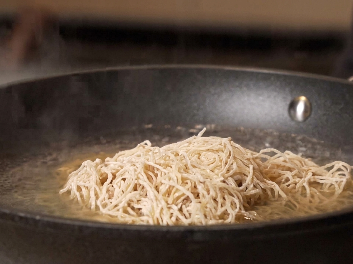 Noodles crudi versati in una pentola di acqua bollente.