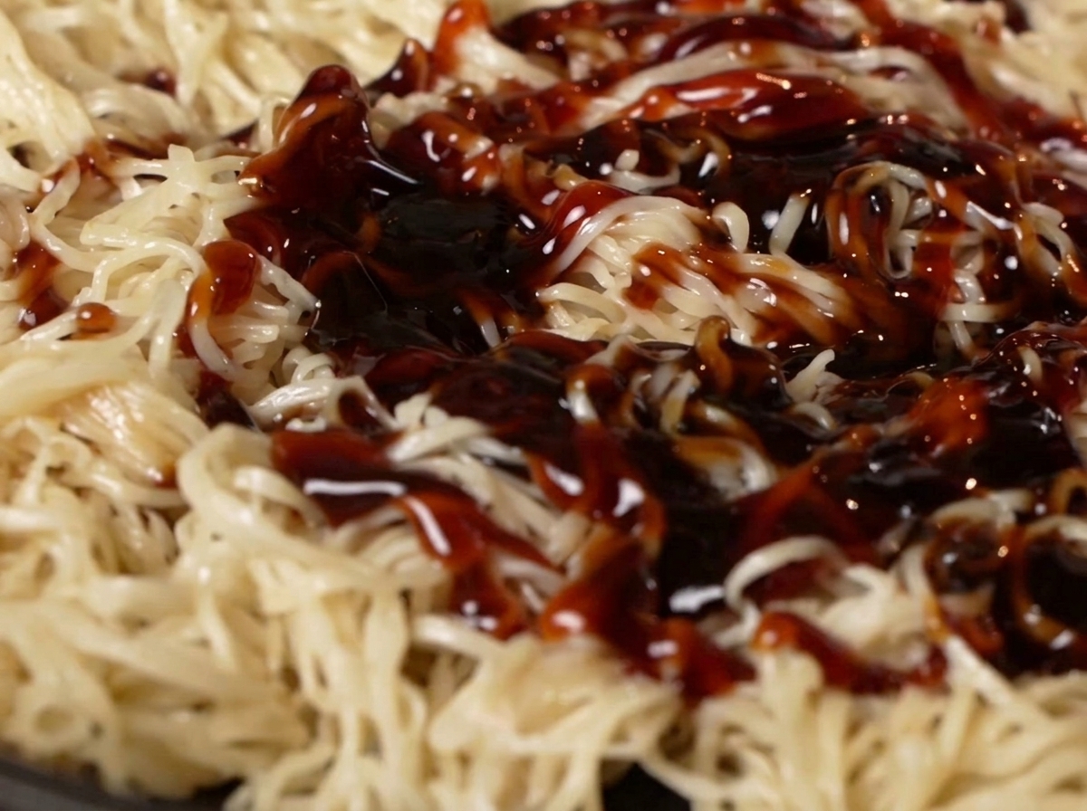 Salsa di ostriche e salsa di soia versate sui noodles in padella.