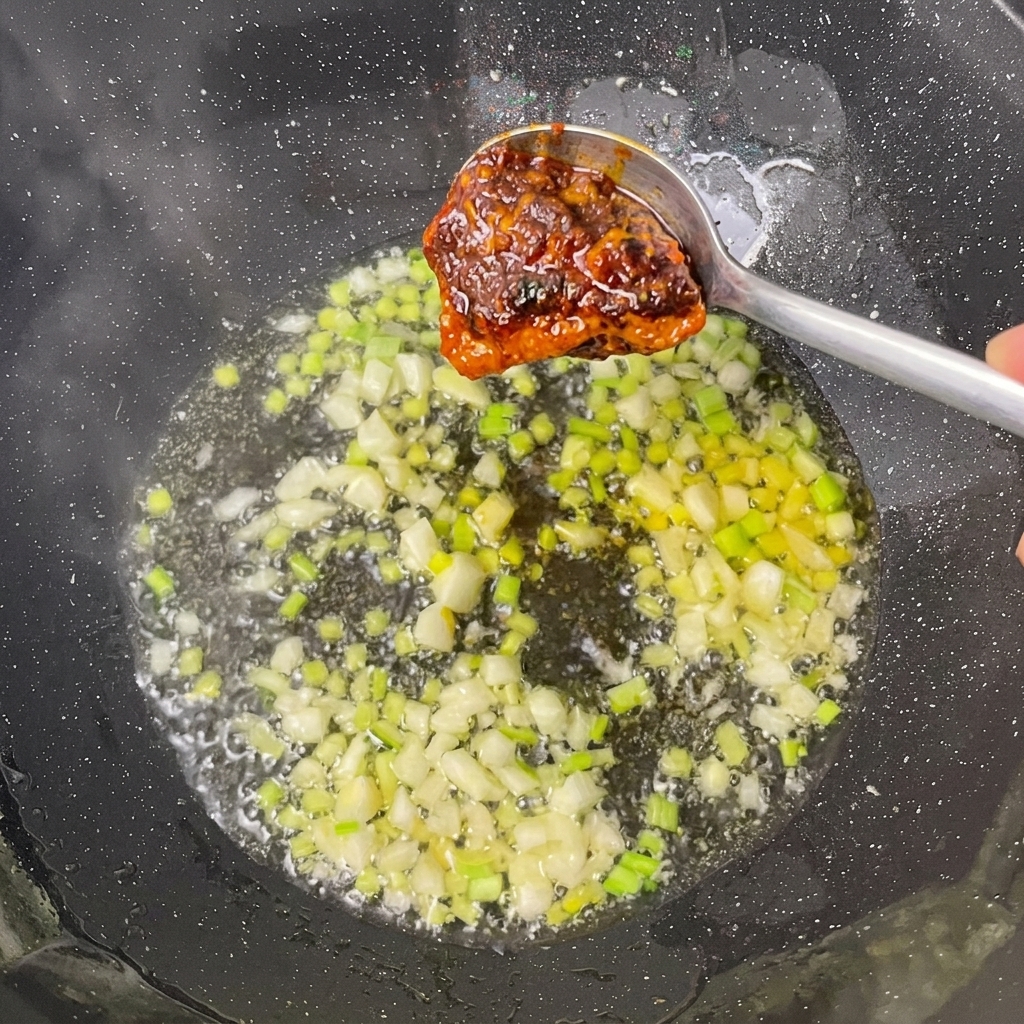 Base per hot pot e pasta di fagioli aggiunte agli aromi nel wok.